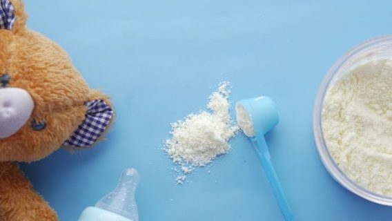 Bear, bottle and baby formula on blue background