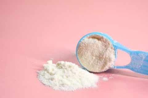 Blue baby formula scoop on pink background