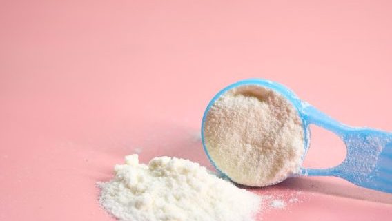Blue baby formula scoop on pink background