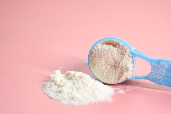 Blue baby formula scoop on pink background