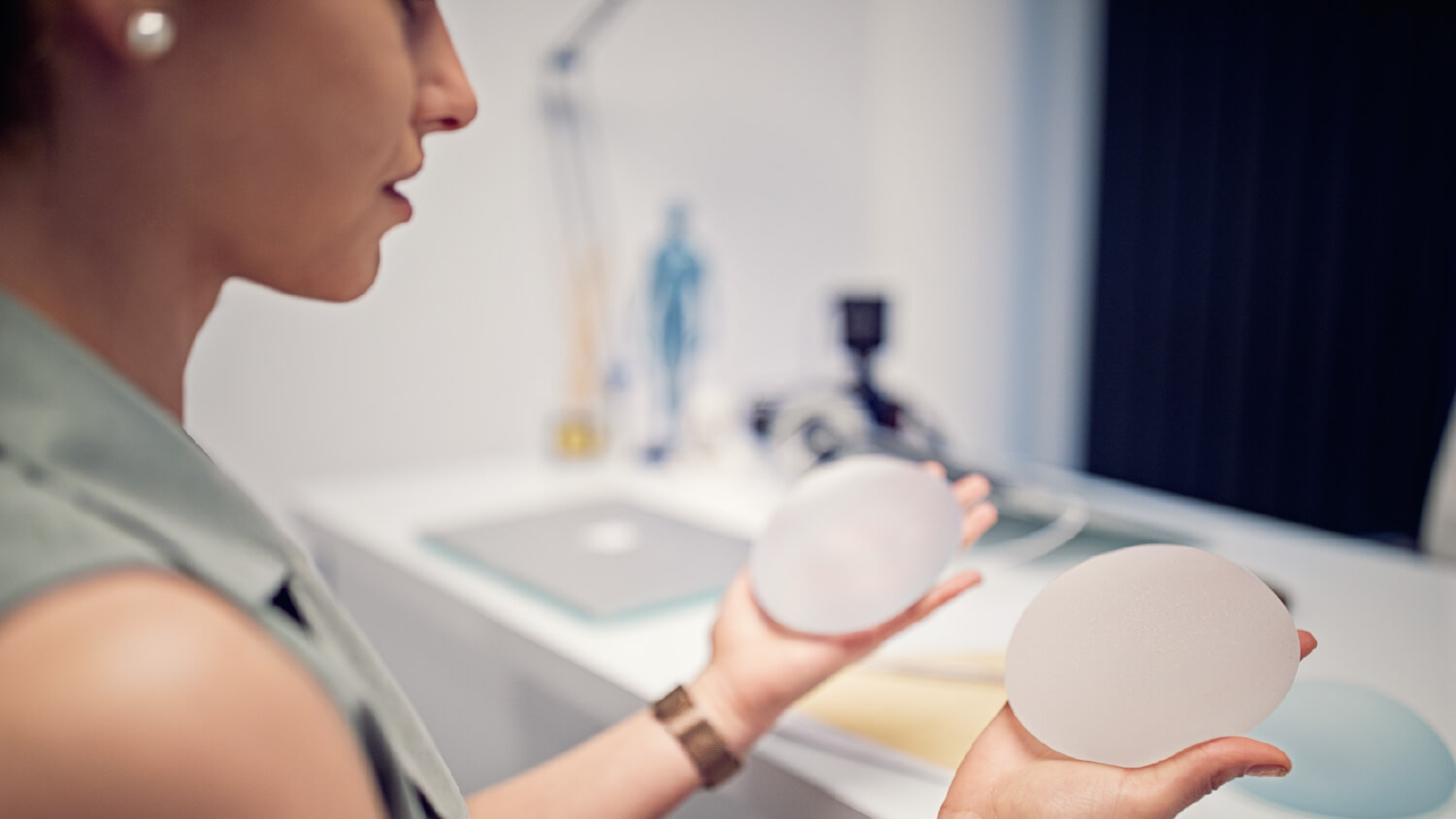 Woman holding breast implants in each hand.