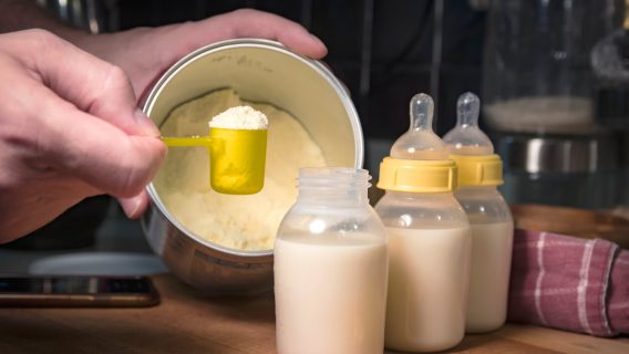 Person scooping infant formula from can