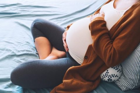 Pregnant woman cradling her abdomen