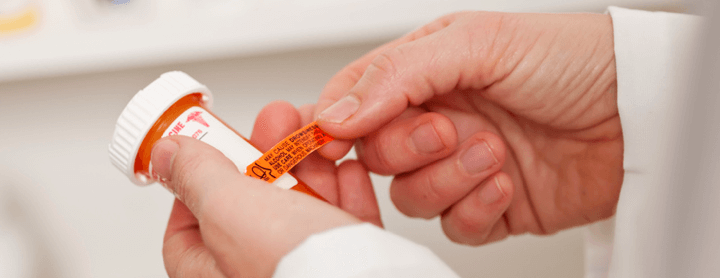 Pharmacist placing auxiliary label on prescription bottle